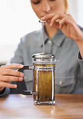 Image showing Woman, closeup or herbal tea to relax in home and warm beverage of herbs mixture in plunger for health. Herbalist, drink or creative idea for dry leaves and wellness for detox liquid on kitchen table