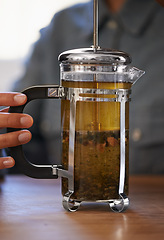 Image showing Closeup, person and hands with tea plunger for brewing, heathy and fresh beverage start morning. Cafe, table and prepare for customers on breakfast to taste, drink and enjoy for beautiful day.