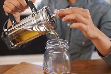 Image showing Closeup, person and hands with brewing tea to start morning, cafe and table before work. Plunger, pour, fresh and healthy beverage for customer on breakfast, teapot and drink to enjoy beautiful day