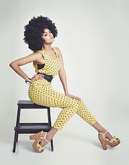 Image showing Black woman, portrait and retro in studio, vintage and hand on waist, unique and dots in clothes. Fashion, hippy and person with hair, model and strong African lady, yellow and girl sitting in chair