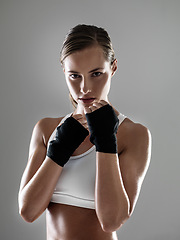 Image showing Serious woman, portrait and boxer with fist straps in fitness, fight or workout exercise on a gray studio background. Young female person or fighter ready for practice, competition or sports training