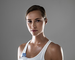 Image showing Woman, portrait and fitness with sweat or water bottle for hydration after workout on a gray studio background. Face of female person or athlete with liquid or drink for exercise, health or wellness