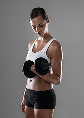 Image showing Woman, fitness and weightlifting with dumbbell for muscle gain, workout or exercise on a gray studio background. Active female person or bodybuilder with weight for arm or bicep curl on mockup space