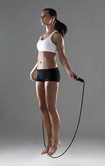 Image showing Woman, fitness and jumping with rope in cardio workout, exercise or training on a gray studio background. Active female person or athlete skipping in balance, challenge or weight loss on mockup space