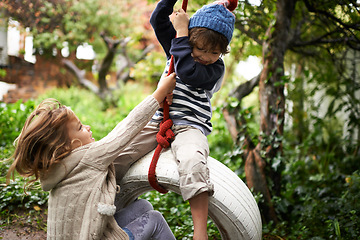 Image showing Children, smile and swing in a backyard in fall together with sibling and fun in garden. Youth, nature and excited on tire in autumn at home outdoor with kids playing by tree with happy girl and boy
