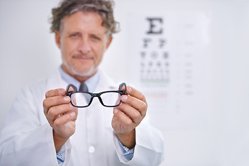 Image showing Glasses, eye exam and portrait of optometrist in clinic to check or test vision in healthcare. Mature, doctor and reading letters on wall in medical assessment or consultation for contact lenses