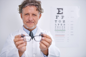 Image showing Glasses, test and portrait of optometrist in clinic to check vision and eye exam in healthcare. Mature, doctor and reading letters on wall in medical assessment or consultation for contact lenses