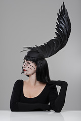 Image showing Fashion, woman and hat with feather in studio for glamour, style and thinking with mystery. Female person, confidence and cap with wing for elegance, luxury and designer clothes on gray background