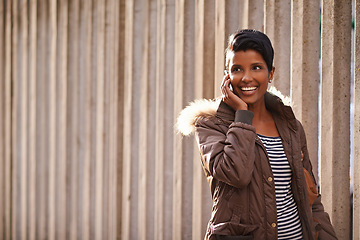 Image showing Woman, smile and cellphone for call, discussion and communication with winter jacket. Reporter, technology and happiness for conversation, collaboration and concrete wall for walk and urban city