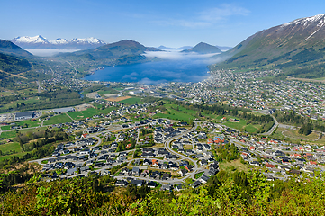 Image showing Majestic mountain town overlooking a misty fjord at dawns first 