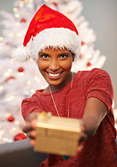 Image showing Happy, santa hat and portrait of woman with present at her home for christmas event, party or celebration. Smile, holidays and face of female person with festive xmas tree and gift on sofa at house.