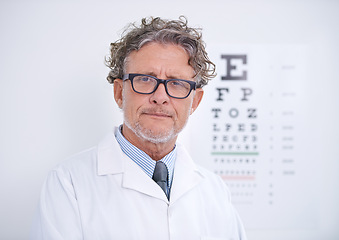 Image showing Test, eye and portrait of optometrist in clinic with glasses to check vision and exam in healthcare. Mature, doctor and reading letters on wall in medical assessment for contact lenses or eyesight