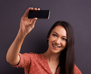 Image showing Woman, selfie and social media post for online connection on studio for profile picture, technology or grey background. Female person, smile and internet communication or streaming, vlog or mockup