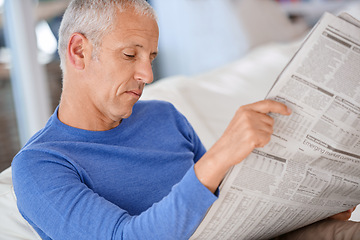 Image showing Senior, man and reading a newspaper on sofa for article, information and morning routine in living room of home. Elderly, person and media paper for global news, knowledge or relax on couch in lounge