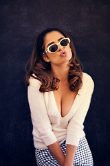 Image showing Woman, fashion and outdoors to blow kiss in style, sunglasses and casual clothes on vacation. Female person, cleavage and flirting for fun on holiday, travel and romantic tourist on wall background