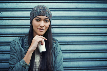 Image showing Woman, fashion and coffee with portrait, urban and city street or background for style. Asian student, beanie and jacket in cape town with winter, cold and planning with metal garage door with denim