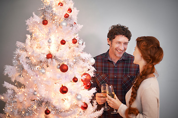Image showing Couple, Christmas and tree with champagne for celebration together for festive season or holiday vacation, decoration or lights. Man, woman and drinking alcohol in home or happy event, love or gifts