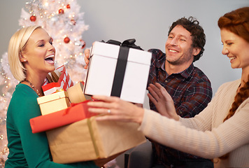 Image showing Friends, Christmas and gift box for celebration at tree for festive season or giving present, vacation or together. Man, women and parcel in living room for winter break or excited, bonding or love