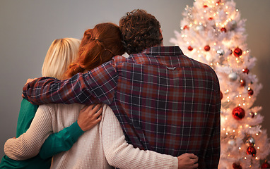 Image showing Friends, embrace and Christmas tree for holiday vacation or festive season bonding, lights or gift giving. Man, woman and back in living room for winter break as relaxing celebration, family or love