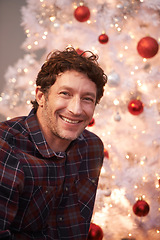 Image showing Portrait, Christmas and man with smile, home and happiness with decorations and festive season. Face, Xmas tree and apartment with celebration and excited with guy and cheerful with lights or person