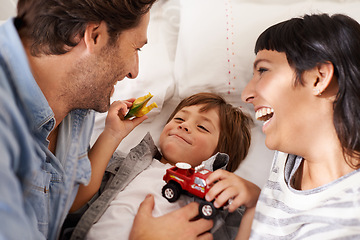 Image showing Family, toys and kid playing in bedroom together for bonding, having fun and entertainment in home. Childhood development, Australian man and woman with child for joke, laughing and relax on bed