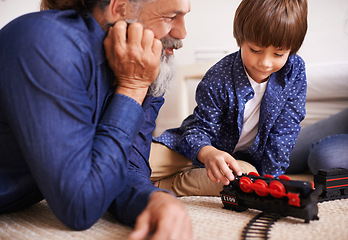 Image showing Grandfather, grandson and play with toy, train and fun in home or house with joy. Man, child and happiness with smile, youth and childhood development for future growth and bonding or care together