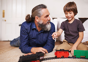 Image showing Father, child and play with toy train and joy in home or house with fun. Mature man, kid and happiness with smile, youth and childhood development for future growth and bonding or care together