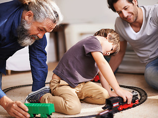 Image showing Men, boy and playing with train toys, together for family time and fun with plastic railway track at home. Grandfather, father and kid with generations for games, playful and happy with bonding