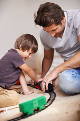 Image showing Man, boy and playing with train toys, together for family time and fun with plastic railway track at home. Father, child and excited youth for games, playful and happiness with bonding in playroom