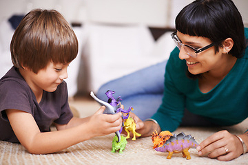 Image showing Mother, child and toy with dinosaur, floor and play for joy or fun at family home or house. Woman, kid and bedroom with bonding, childhood and future development or growth for happy care together