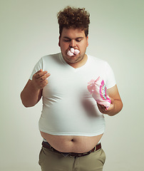 Image showing Obesity, weight gain and humor for man in studio with marshmallow for unhealthy eating, sugar and candy. Overweight person with sweets in mouth and fat stomach for greed, comedy and funny indoor