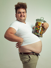 Image showing Candy, jar and portrait of man in studio for luxury snacks, sweets and dessert in container. Comic, funny and food, isolated and plus size person with glass for unhealthy diet on background.