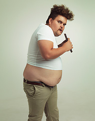 Image showing Chocolate, portrait and plus size man with eating food, dessert and candy in a studio. Nutrition, sweet and unhealthy snack with sneaky and secret with a hungry male person with green background