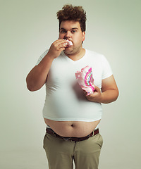 Image showing Plus size, candy and portrait for man in studio with marshmallow for unhealthy eating, sugar and confection. Young person with sweets in mouth and round stomach for greed, comedy and humor indoor