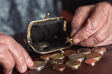 Image showing Detailed closeup photo of elderly 96 years old womans hands counting remaining coins from pension in her wallet after paying bills. Unsustainability of social transfers and pension system.