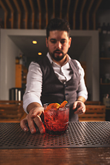 Image showing Bartender serving a craft cocktail at a bar