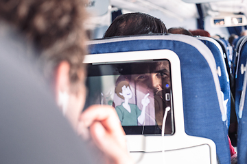 Image showing Reflection of a passenger on an airplane touch screen monitor while watching cartoon during long flight. Entertainment service system in aircraft.