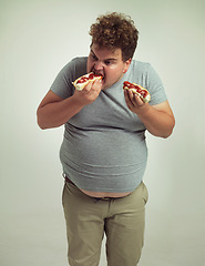 Image showing Plus size man, fast food and eating hotdogs for lunch in studio background for snack, hunger and craving. Male person, hungry and takeaway meal with ketchup or starving and enjoy while standing