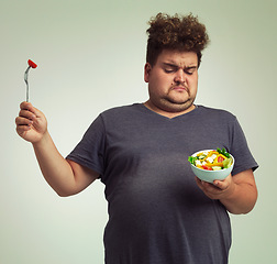 Image showing Studio, unhappy man and salad with bowl for healthy meal, diet and nutrition for weight loss. Plus size, male person and disgust expression with organic food for wellness, detox or lifestyle change