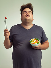 Image showing Plus size man, salad and diet with healthy food with fork, bowl and vegetables for wellness on studio background. Male person, frustrated and lose weight for health, eating disorder and nutrition