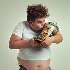 Image showing Love, candy and plus size man kissing glass jar in studio on gray background for craving or hunger. Food, obsession or possessive and crazy young person with lots of sugar for unhealthy eating