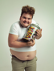 Image showing Candy, jar and portrait of crazy man in studio for snacks, sweets and dessert in container. Comic, funny and overweight, isolated and plus size person with glass for unhealthy diet on background