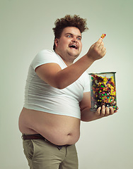 Image showing Excited, man and happy with candy in studio for treat, snack and cheerful with unhealthy diet. Plus size, male person and jar of sweets with sugar food for happiness, enjoyment and satisfaction