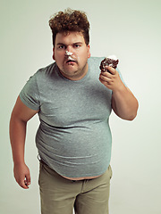 Image showing Plus size, eating and portrait of man with cake in studio for unhealthy, sugar and sweet snack. Greedy, food and male person with messy slice of chocolate dessert isolated by gray background.