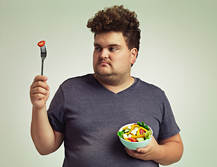 Image showing Plus sized, man and unhappy with food for healthy diet, fork or bowl and salad for wellness on studio background. Male person, detox and lose weight for health, eating disorder and nutrition