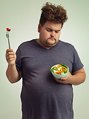 Image showing Unhappy, man and salad for diet with healthy food, fork or bowl and vegetables for wellness on studio background. Plus size person, fresh meal and lose weight for health, eating disorder or nutrition