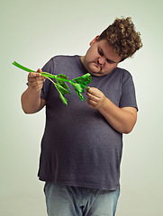 Image showing Plus size, diet and unhappy man with vegetable for health benefits, nutrition and wellness in studio in white background. Weight loss, celery and male person for healthy food, wellbeing and detox