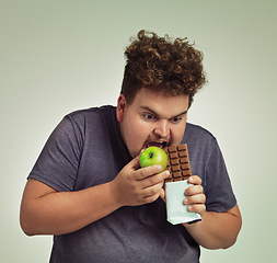 Image showing Person, apple and chocolate in studio with choice of junk food, sweet or diet for wellness. Plus size, man eating and decision, fruit or candy for nutrition, lose weight and healthy lifestyle