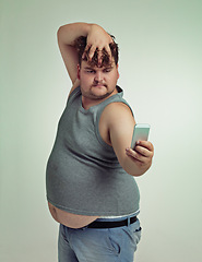 Image showing Selfie, cellphone and plus size man in studio posing with casual, trendy and cool outfit with stomach. Phone, serious and funny with male person with photography picture isolated by gray background.