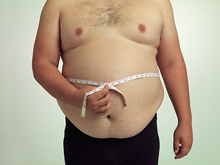 Image showing Man, plus size and body with measurement in studio on white background with tape for progress, weight loss and exercise. Positivity, fitness and stomach with self care to monitor health and shape